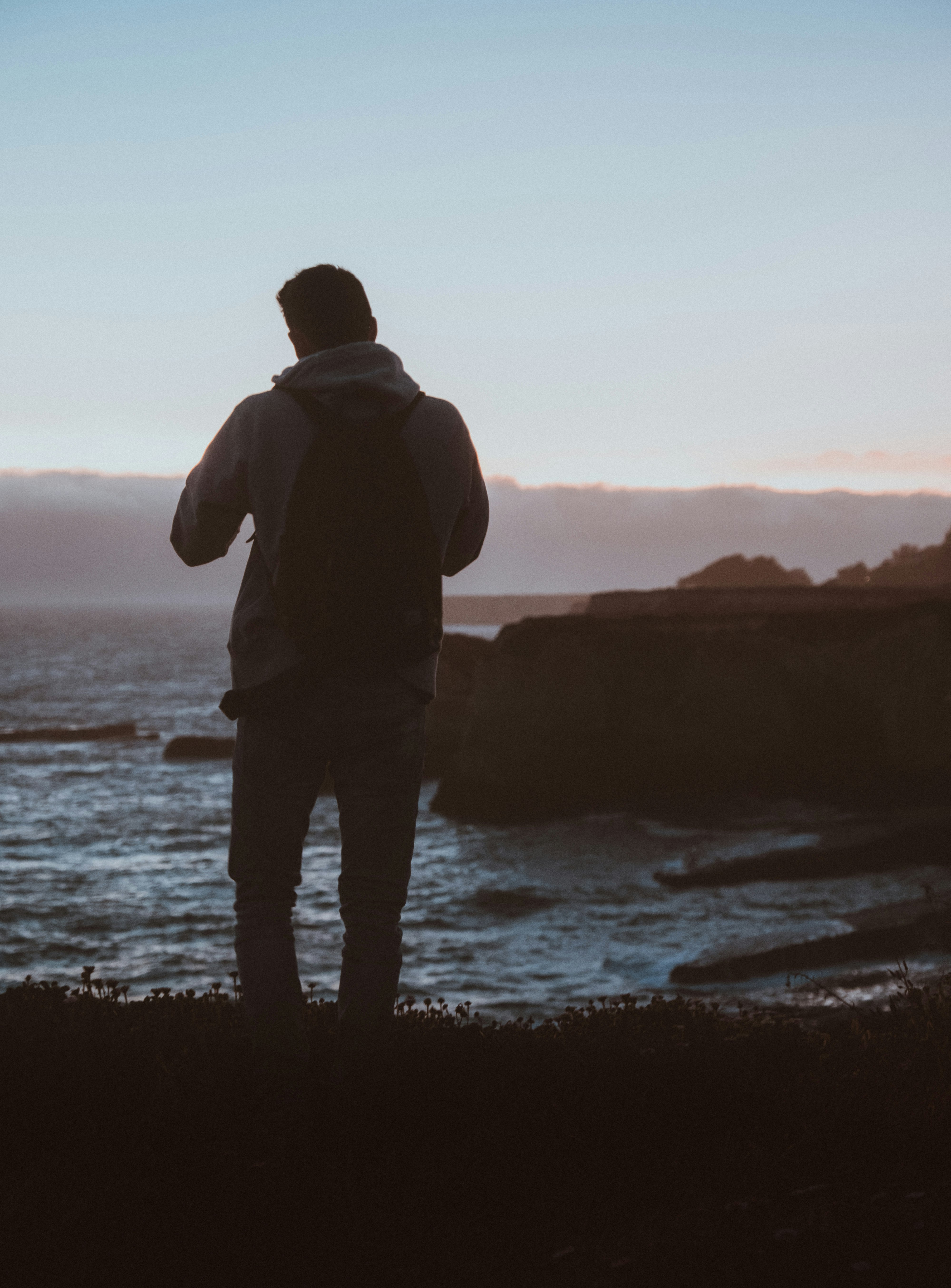 man standing beside body of water